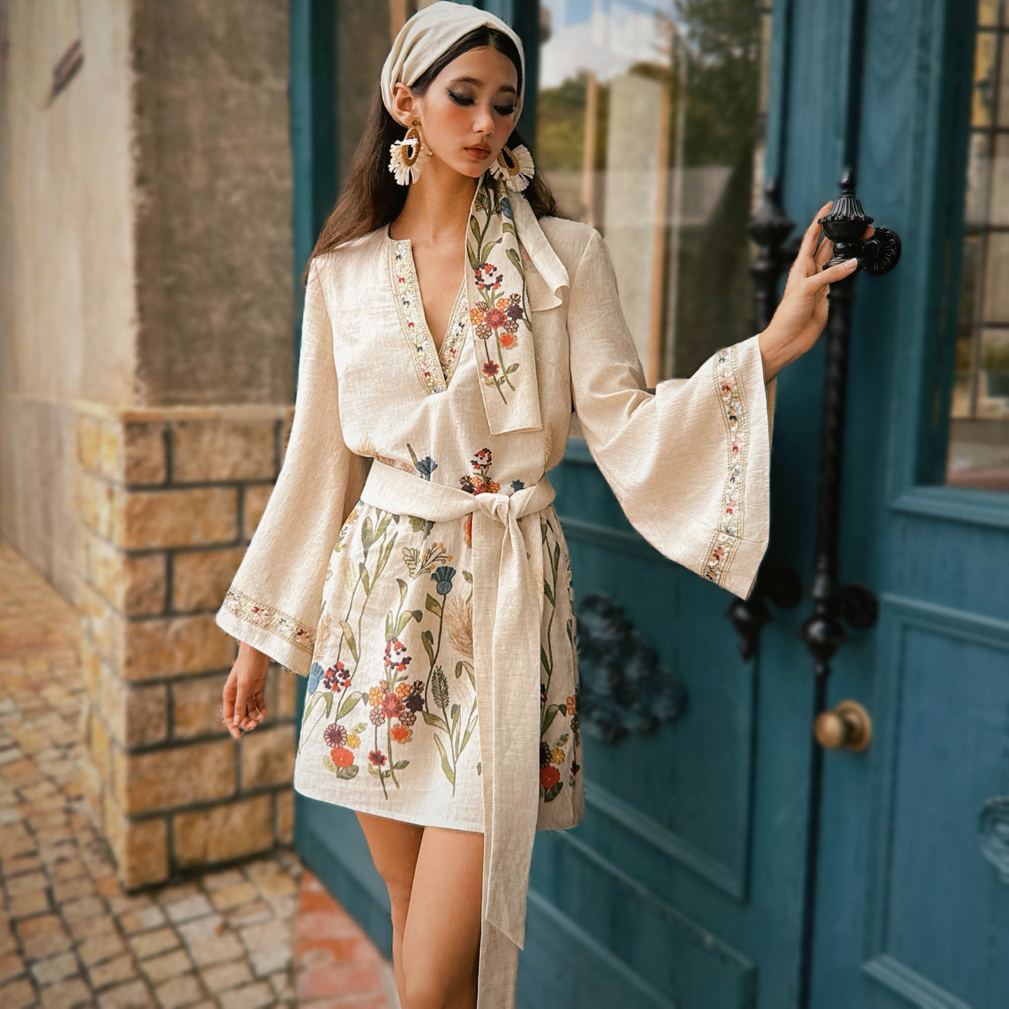 Woman in a floral dress standing in front of a blue door.