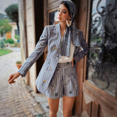 Woman in a stylish outfit standing in front of a building entrance.