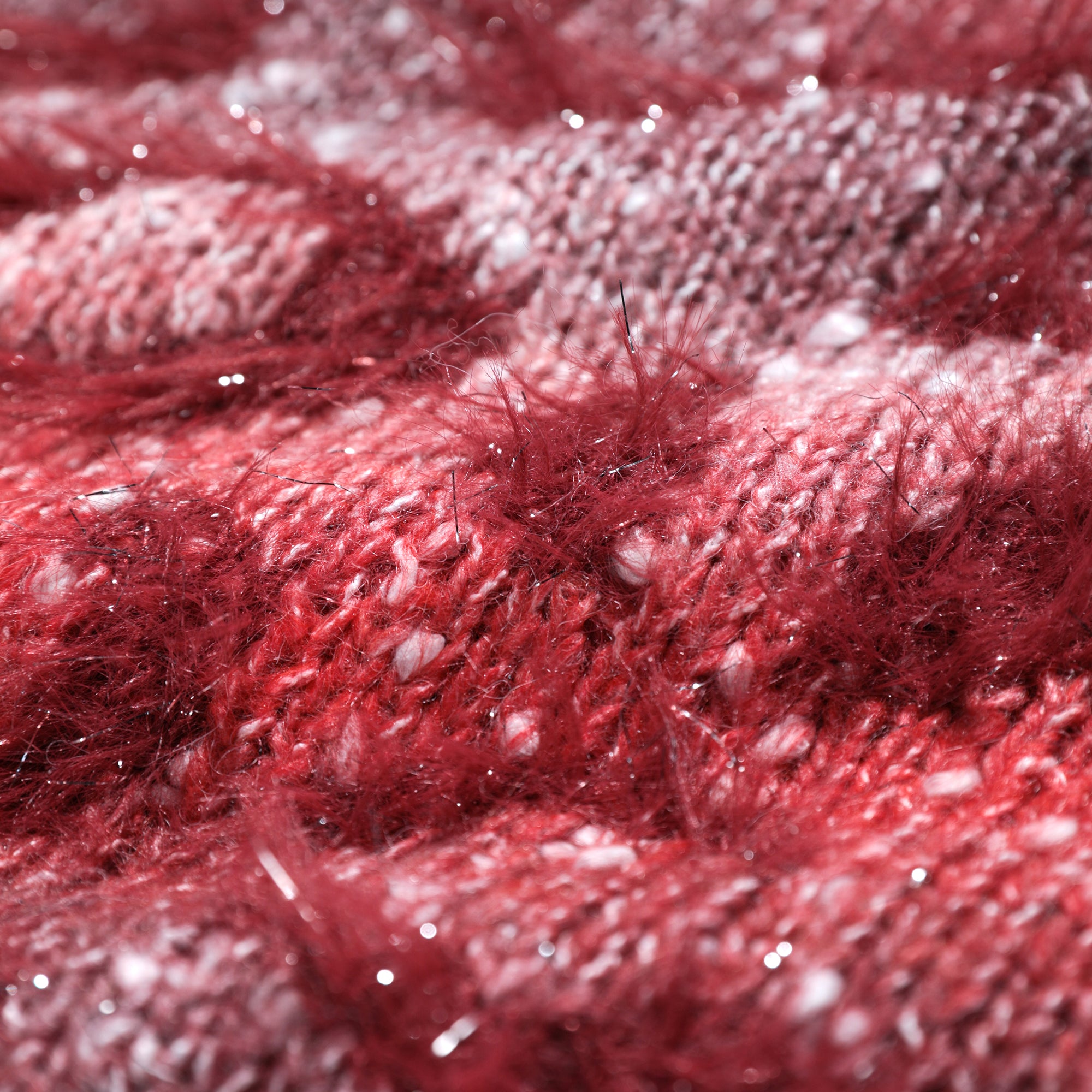 A close-up image of a red and white knitted fabric, with a fuzzy texture and small white specks scattered throughout.