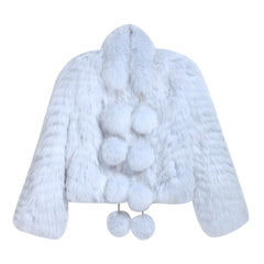 A white fur coat with pom poms hanging from the collar.