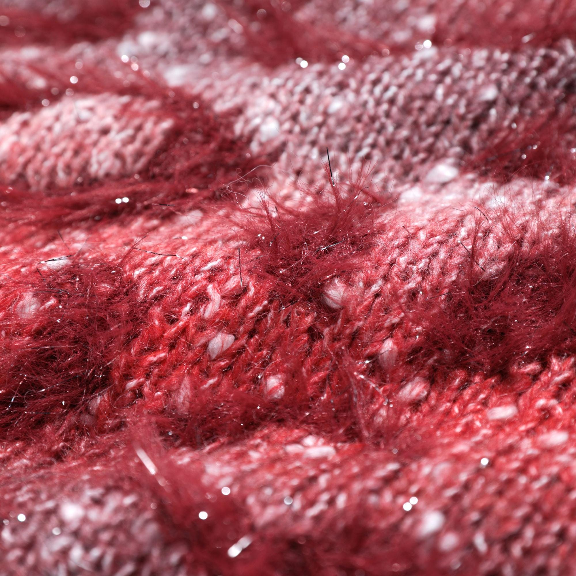 A close-up image of a red and white knitted fabric, with a fuzzy texture and small white specks scattered throughout.