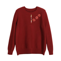 A red knitted sweater with a floral design on the front.