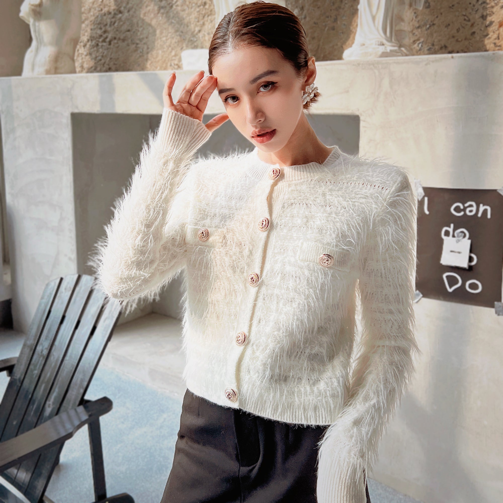 A woman wearing a white cardigan with buttons poses for a photo in an indoor setting.