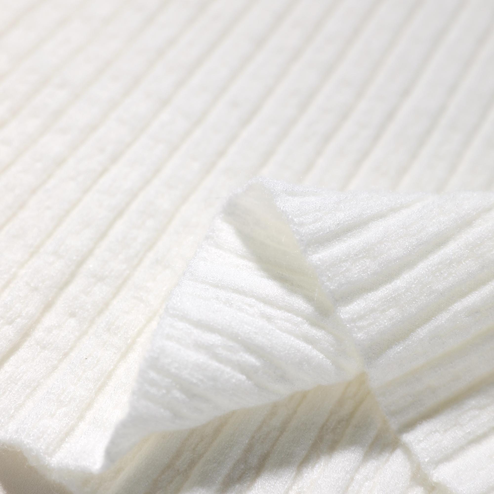 A close-up view of a white fabric with a ribbed texture, featuring a folded edge.