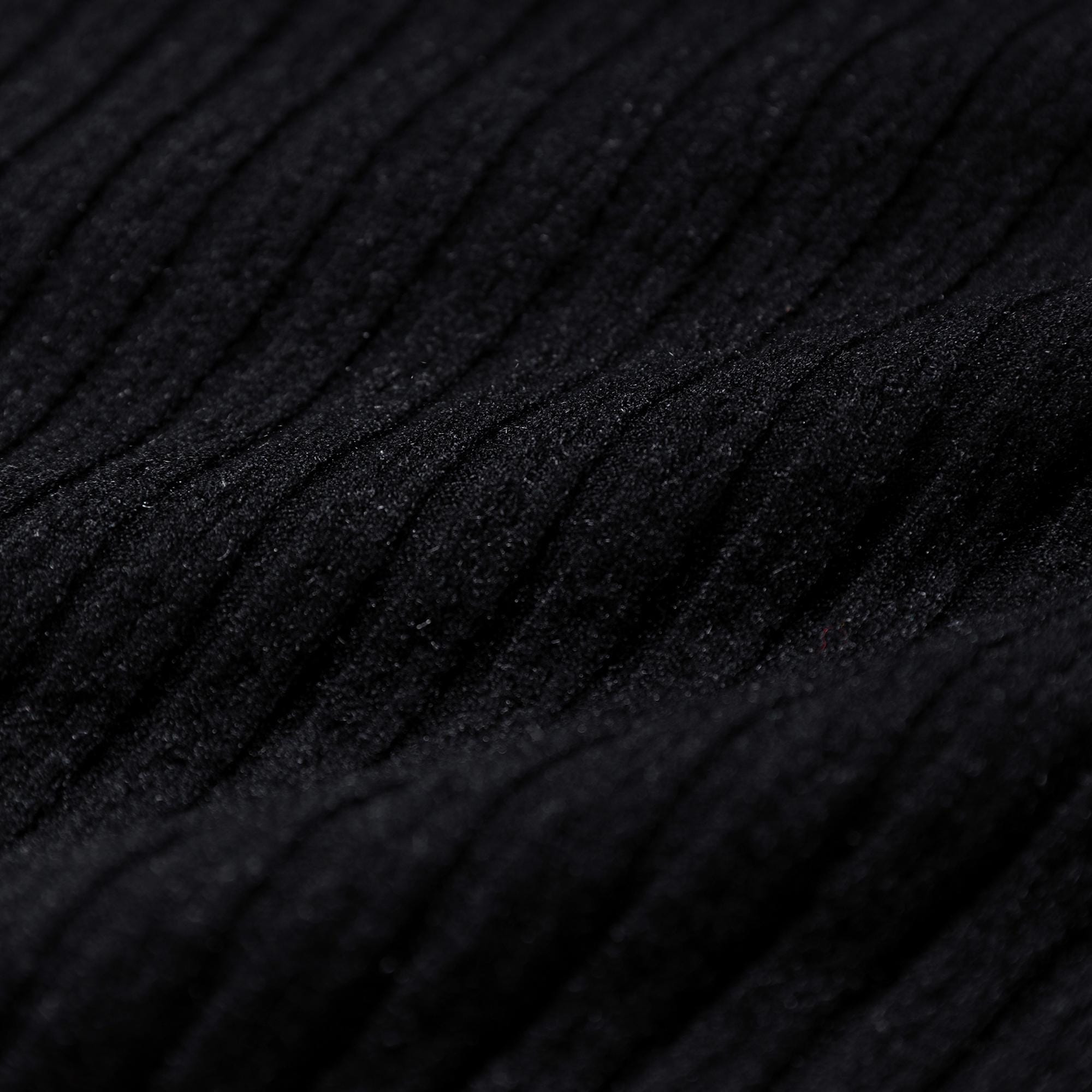 The image is a close-up of a black fabric with a textured, ribbed appearance.