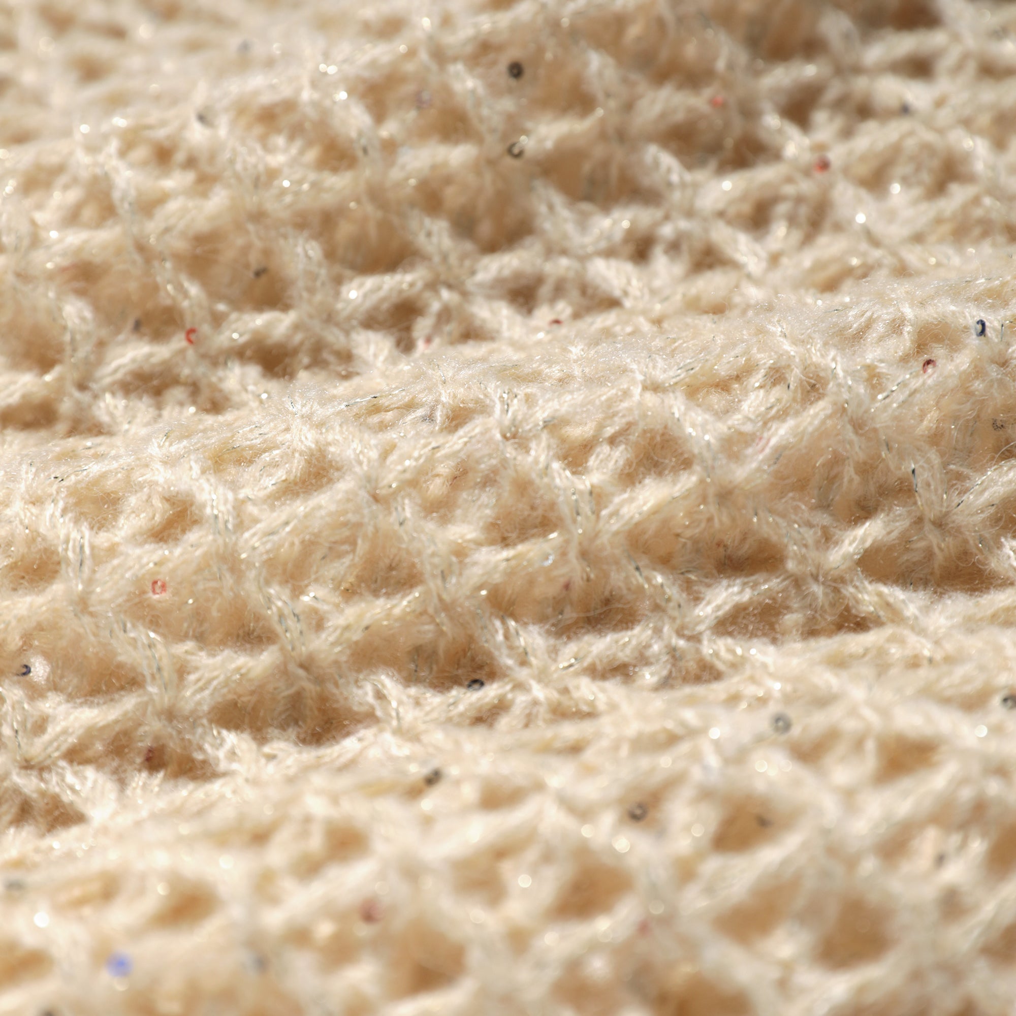 A close-up image of a soft, beige fabric with a textured, woven pattern.