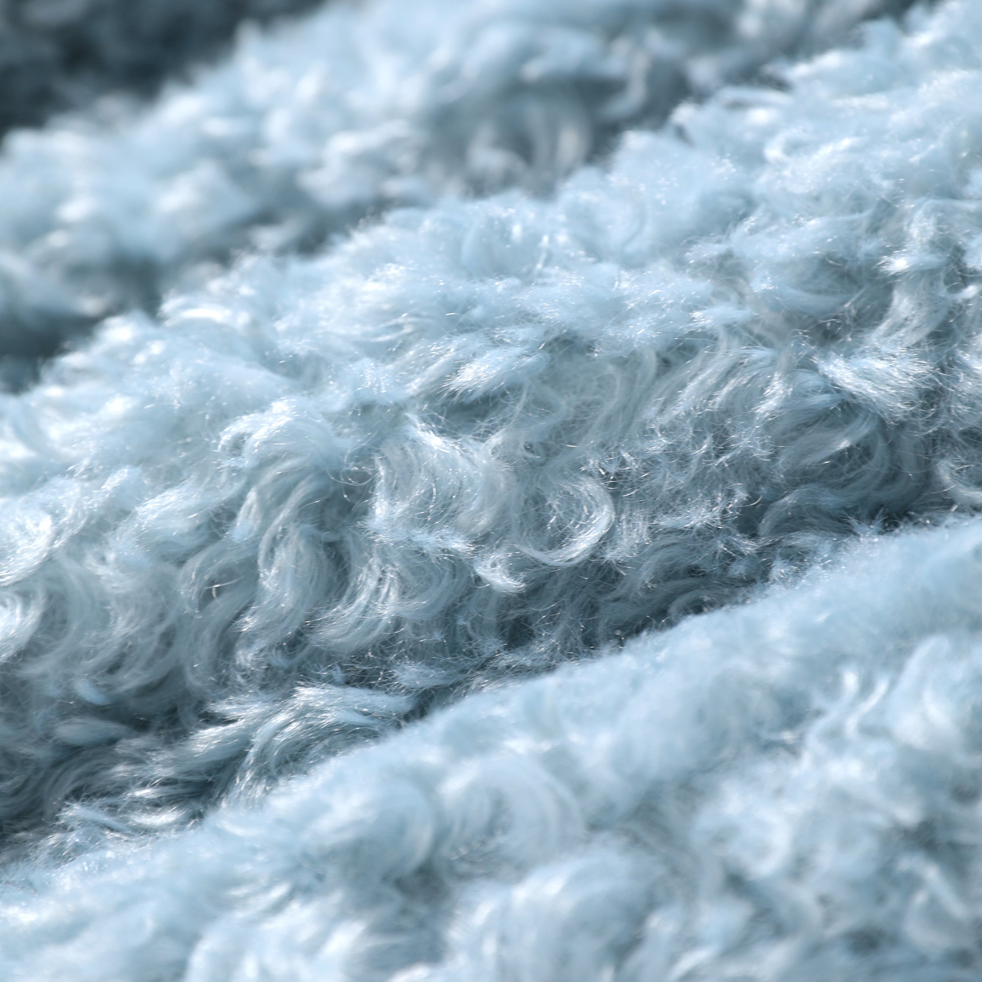 A close-up view of a soft, fluffy, and textured fabric, likely a type of plush material, with a light blue color.