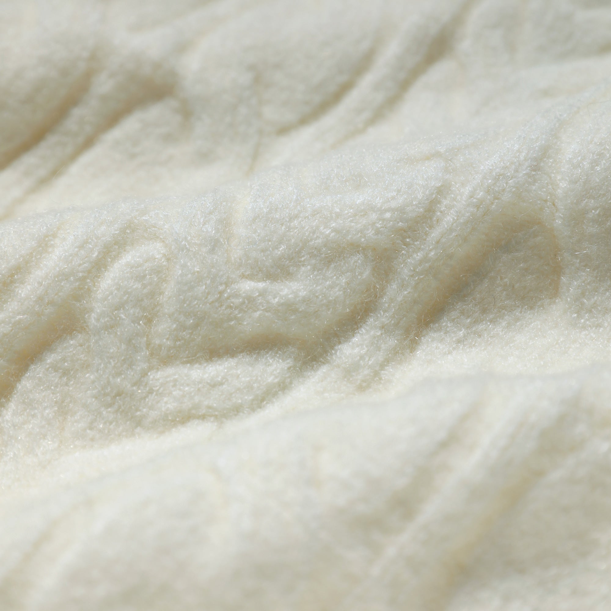 A close-up image of a soft, fluffy white fabric, possibly a blanket or a piece of clothing.