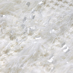 The image is a close-up of a white, fluffy material with a slightly fuzzy texture.