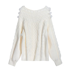A cream-colored knitted sweater with a high collar and pom-pom details.