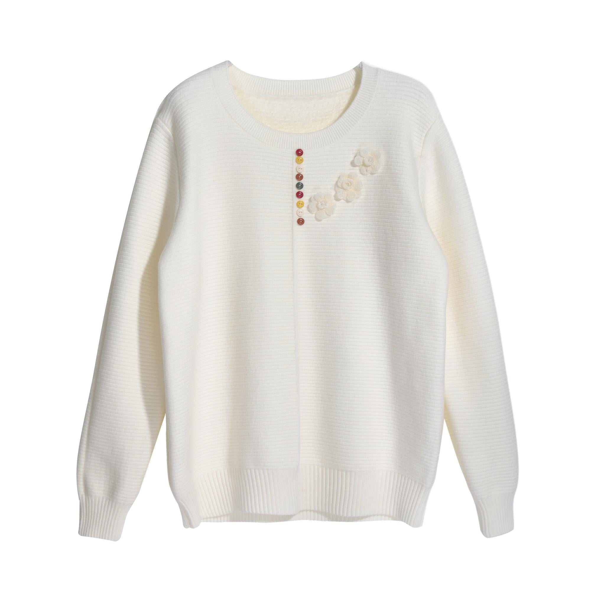 A white knitted sweater with a floral design on the front.