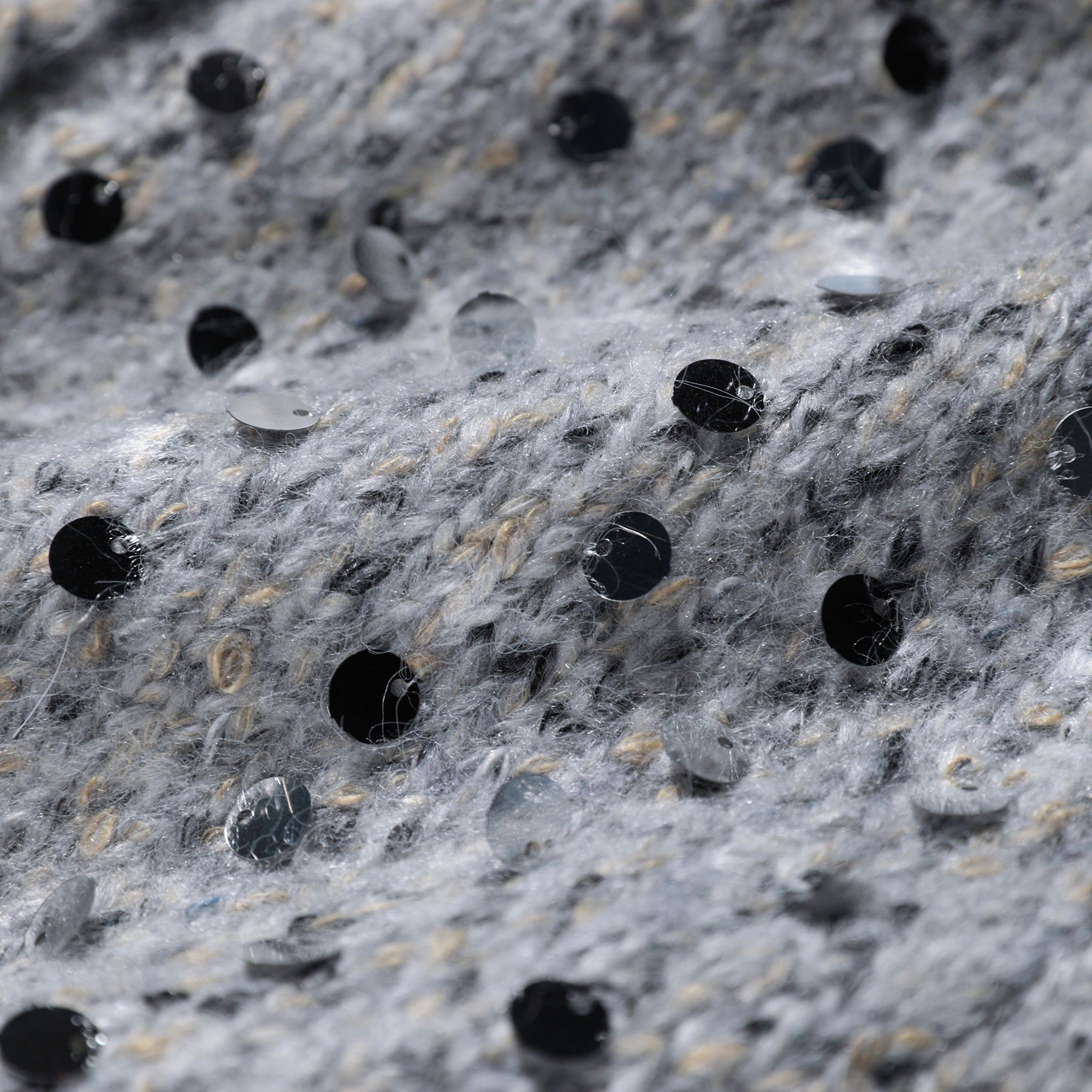 a close-up view of a textured fabric with small black and silver sequins or beads scattered across it.