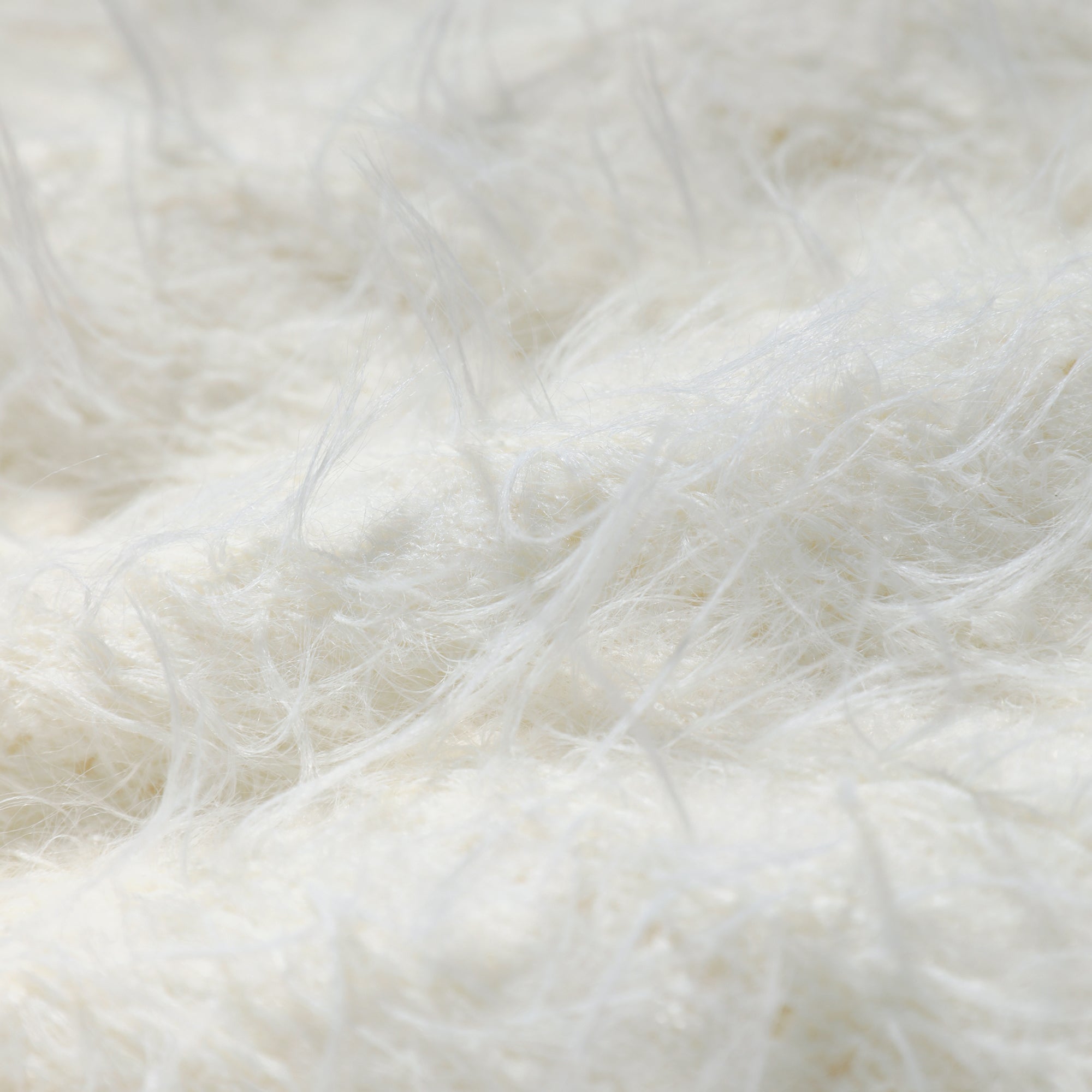 The image is a close-up of a soft, fluffy white fabric, possibly a blanket or a piece of clothing. The fabric appears to be made of a fuzzy material, giving it a soft and cozy appearance.