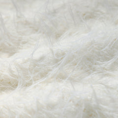 The image is a close-up of a soft, fluffy white fabric, possibly a blanket or a piece of clothing. The fabric appears to be made of a fuzzy material, giving it a soft and cozy appearance.