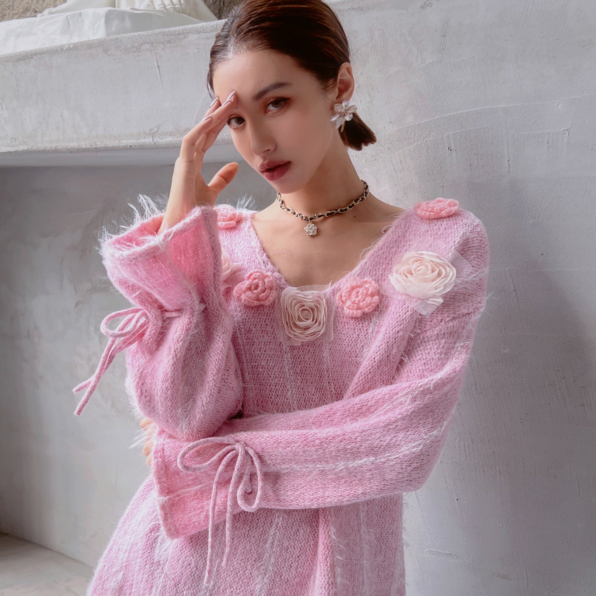 A woman wearing a pink dress with flower accents posing for a photograph.