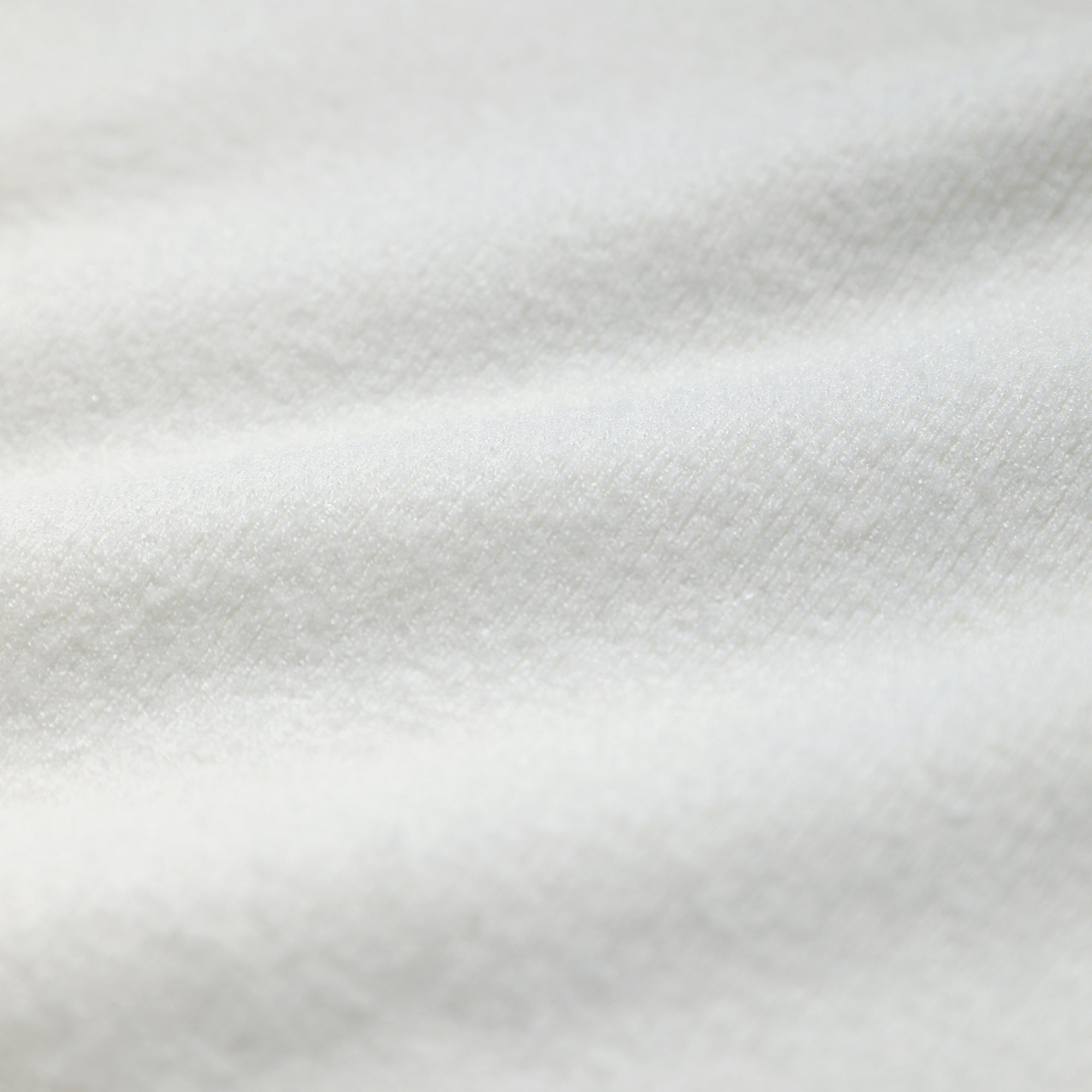 A close-up view of a white fabric, possibly a blanket or towel, with a slightly wrinkled texture.