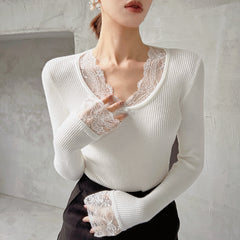 A woman wearing a white lace top and black skirt stands in front of a plain white wall.
