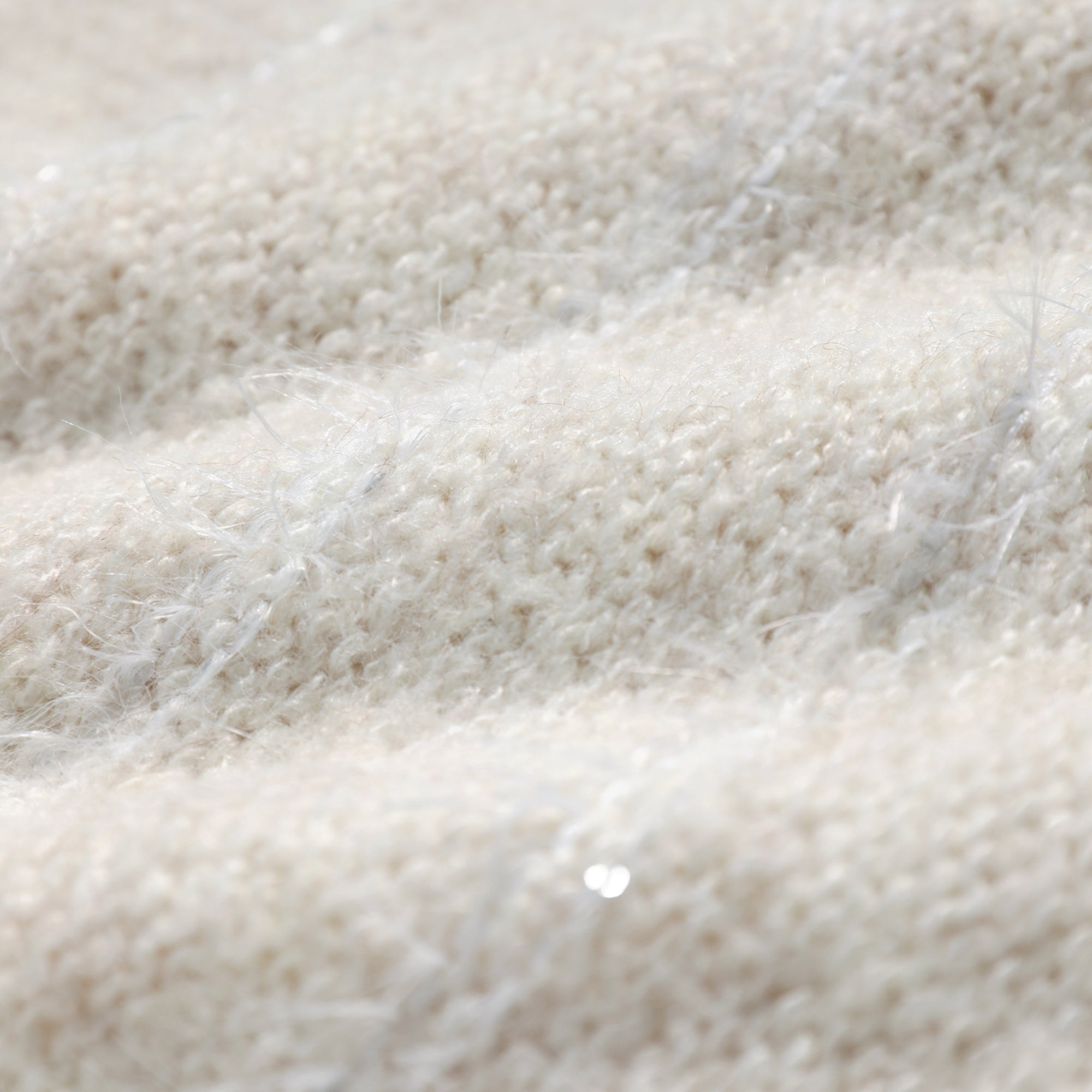 A close-up image of a soft, fluffy white fabric, possibly a blanket or sweater, with a slightly wrinkled texture.
