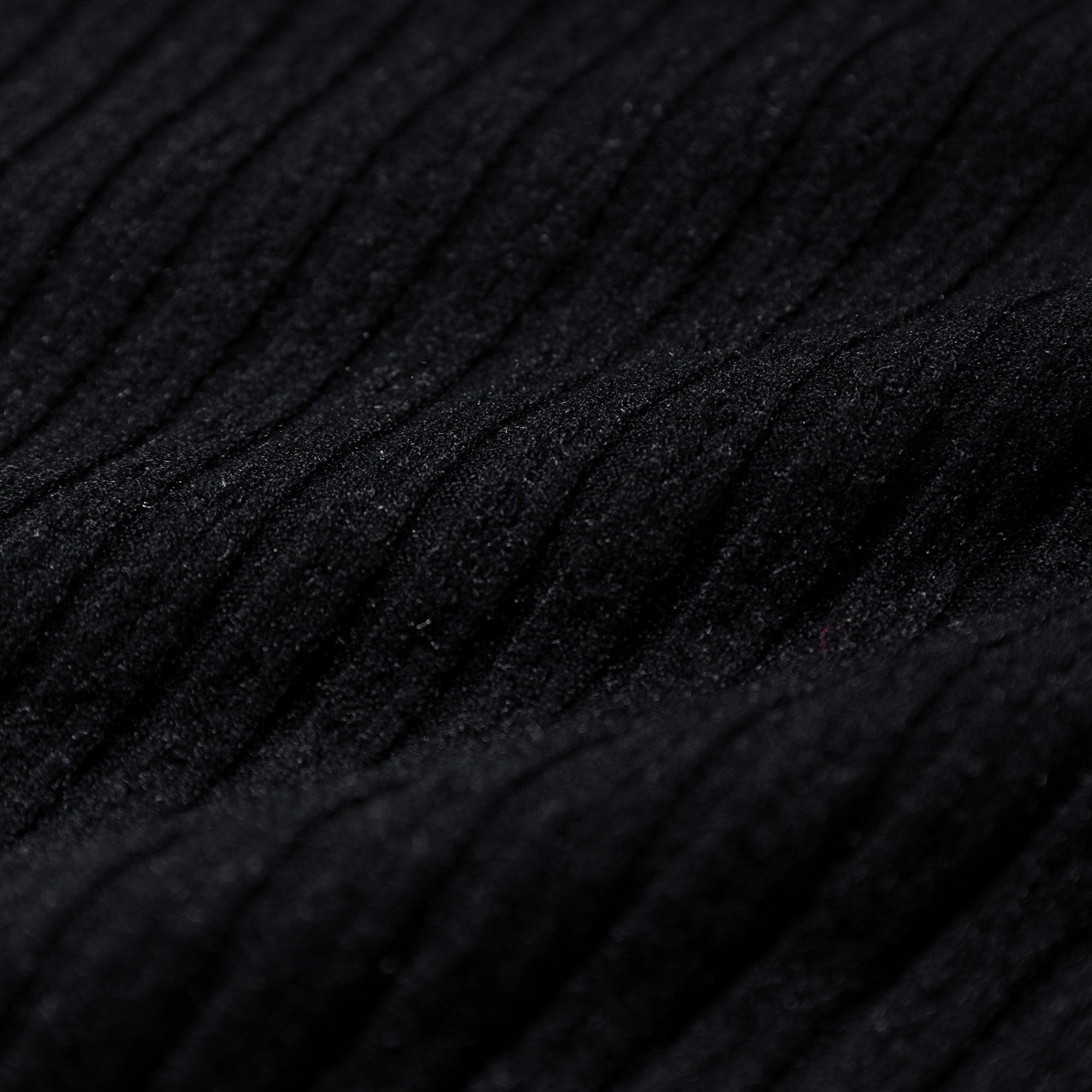 The image is a close-up of a black fabric with a textured, ribbed appearance.