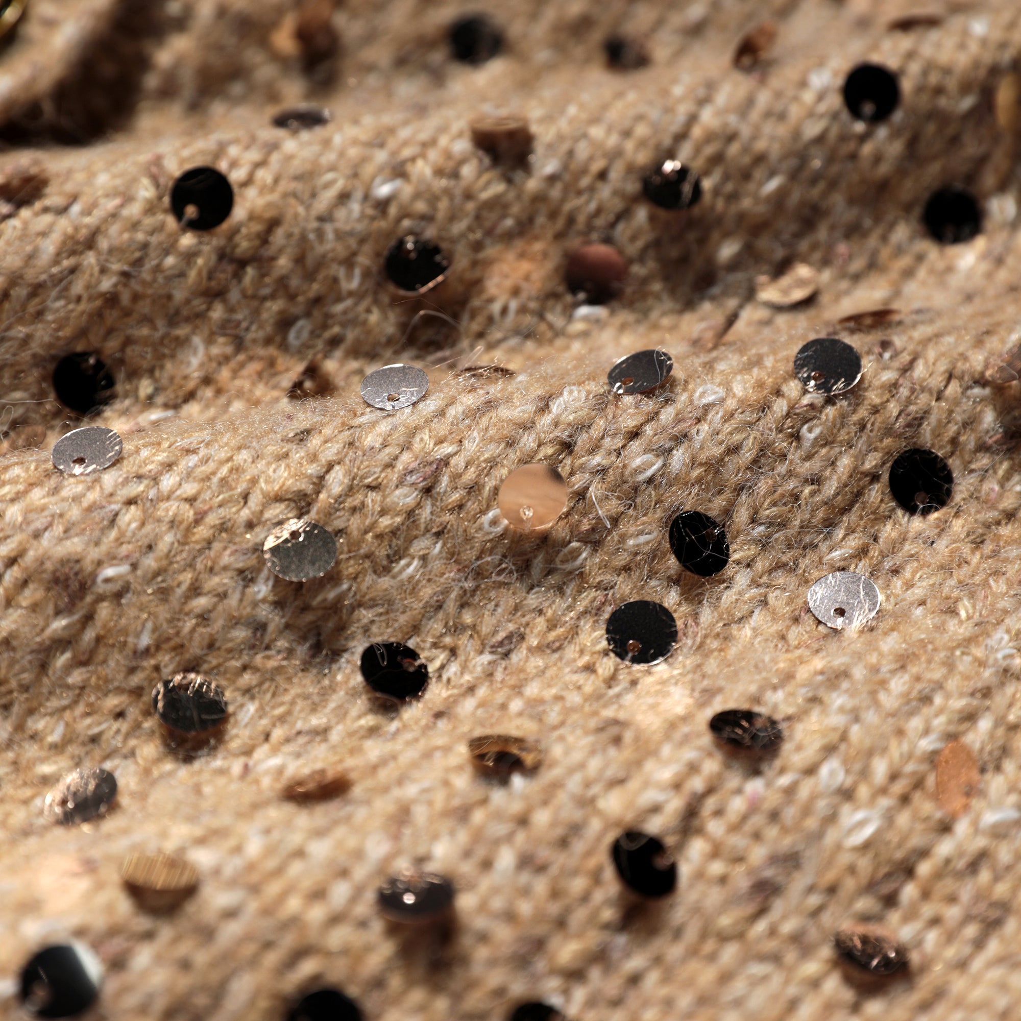 a close-up view of a knitted or crocheted fabric with small circular sequins or beads scattered across it, creating a textured and visually interesting pattern.