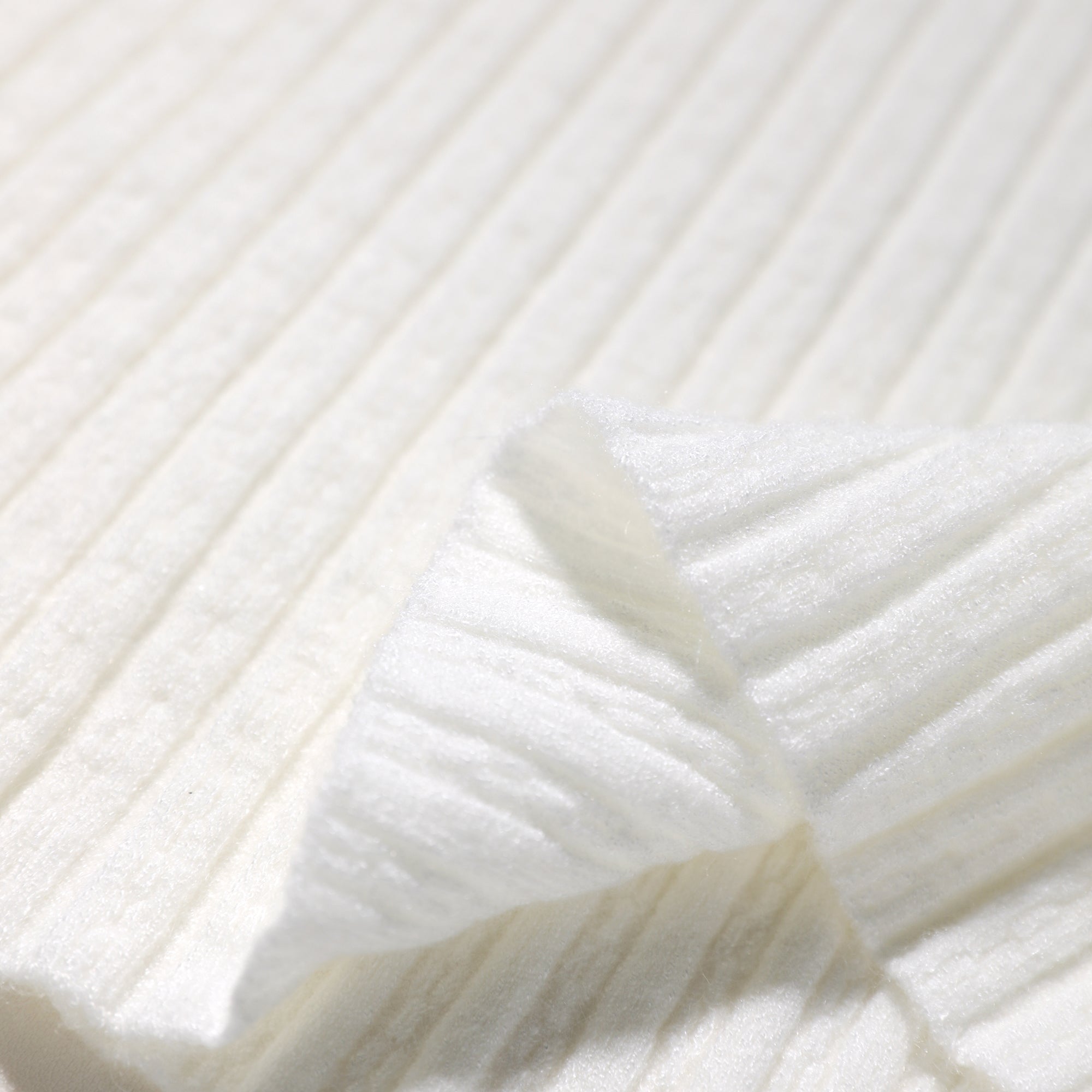 A close-up view of a white fabric with a ribbed texture, featuring a folded edge.